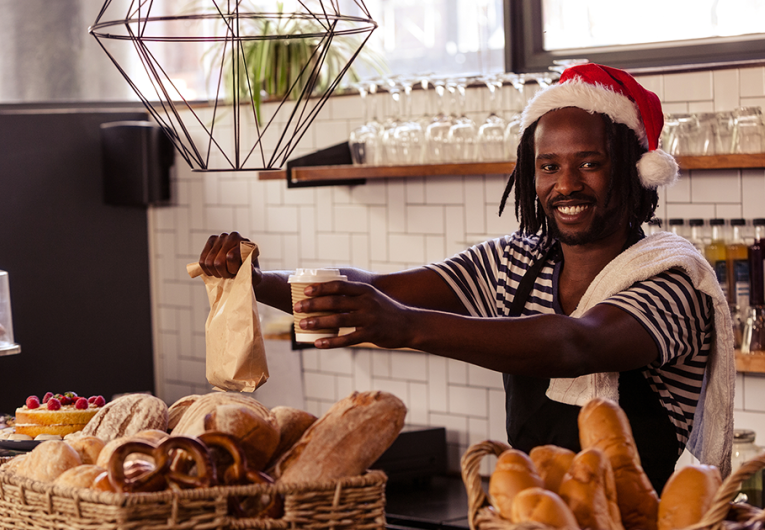 Smiling employee serving take away order at coffee shop