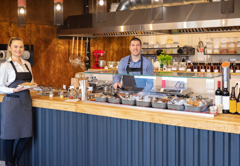 Counter service at modern bistro with smiling waiters serving food 