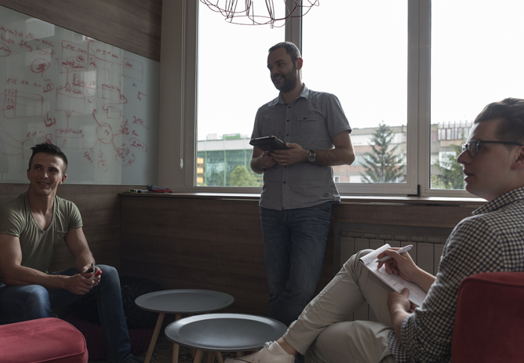 small group of three employees in private office have team meeting and brainstorming while working on laptop and tablet computer