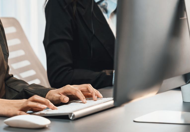 work computers lined up with woman in blazer typing on one