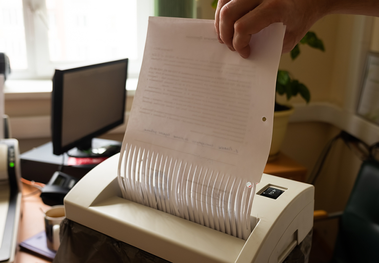 a man destroys paper documents in a shredder.