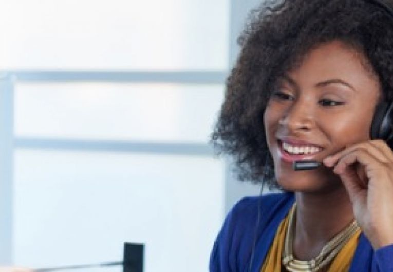 Call center tech talking through a headset in front of a computer