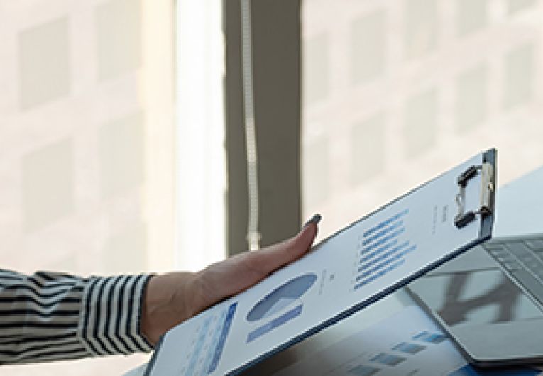 A person looking at a clipboard at a desk.