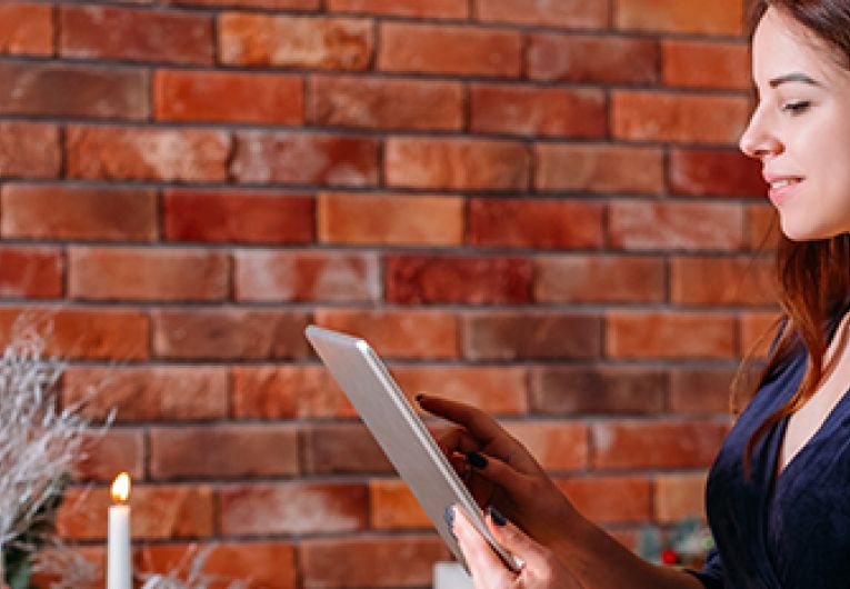 Small Business Owner views mobile device in store decorated for the holidays.