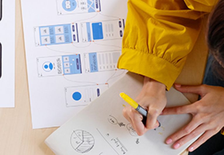 Overhead view of a woman making revisions to designs of a product.