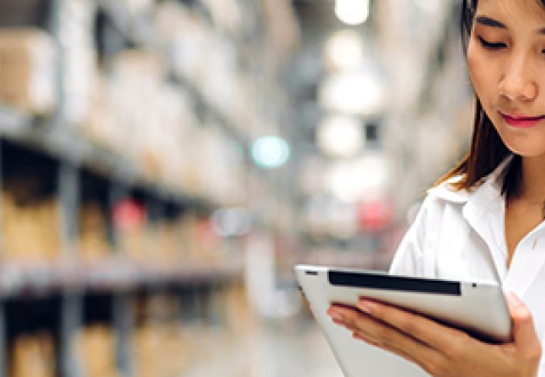 Small Business owner checking supplies using a tablet in a warehouse.