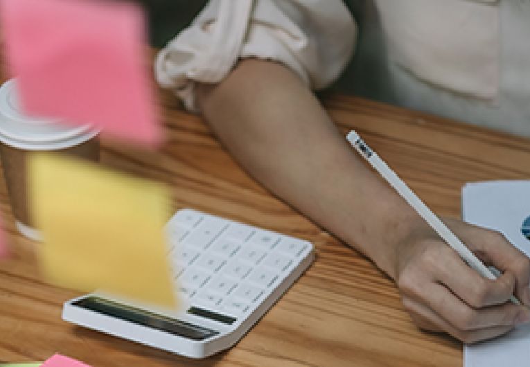 Small Business Owners looking over financial documents with a calculator next to her.