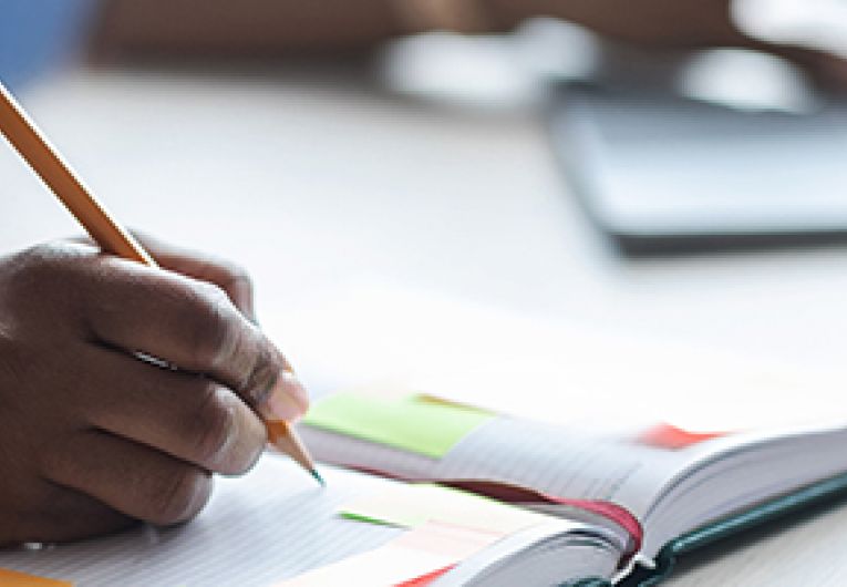 A business professional writing notes in a journal.