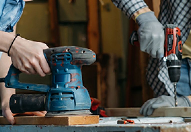 Two people doing woodwork together.