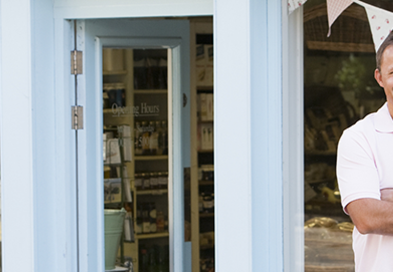 Man stating in front of small business storefront. 