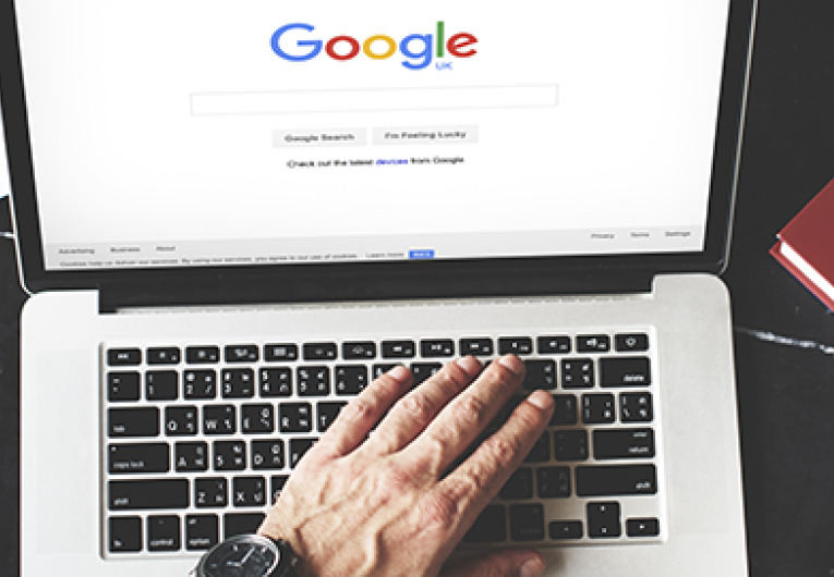 Young Man Browsing Google Website on Laptop