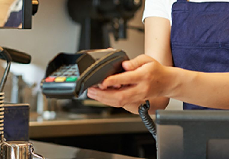 A person holds up a credit card processing machine.