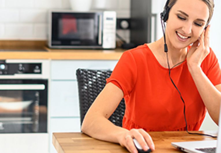 Remote employee wearing a headset working in front of a laptop.