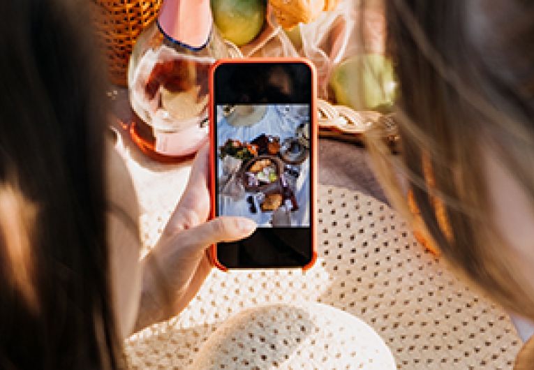 Two small business partners taking a photo of a brunch special at a restaurant for social media.