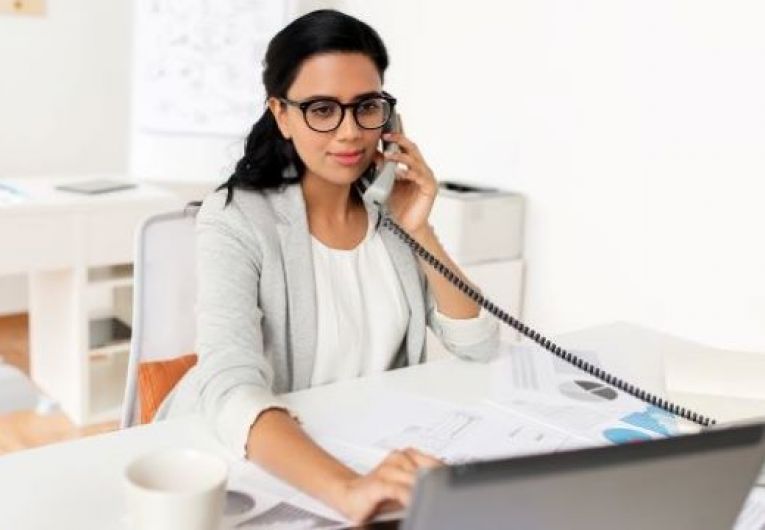 Home business owner talking on the phone while viewing a laptop