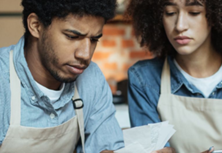 Two business owners of a coffee shop look over financial statements.