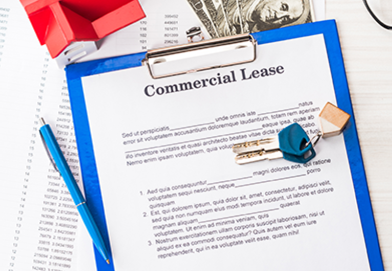   Save Download Preview top view of document with commercial lease lettering on clipboard near keys, house model, pen, calculator, magnifier, money and glasses
