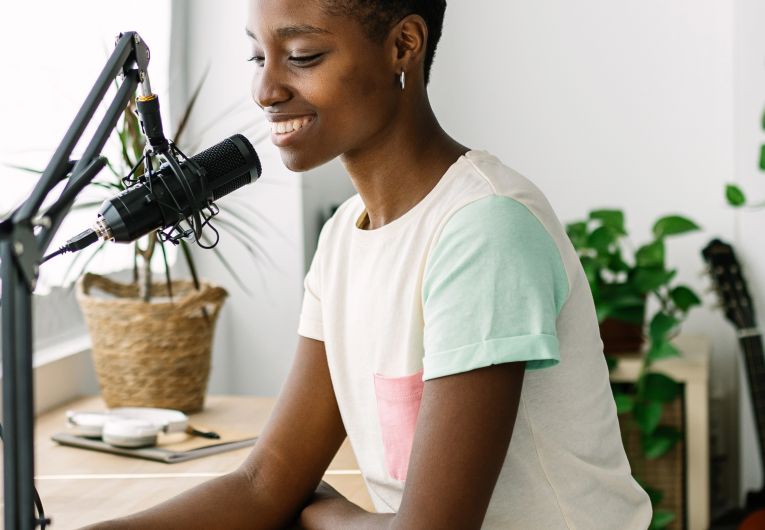 woman recording podcast on laptop with mic