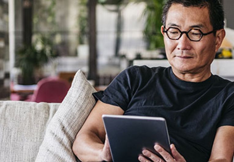 man sitting on couch using a tablet