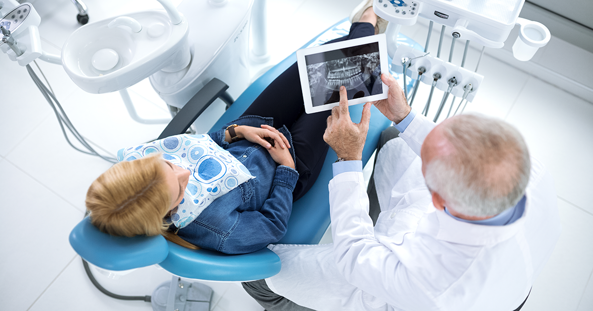 Dentist and patient looking at x-ray of teeth in a dentist's office