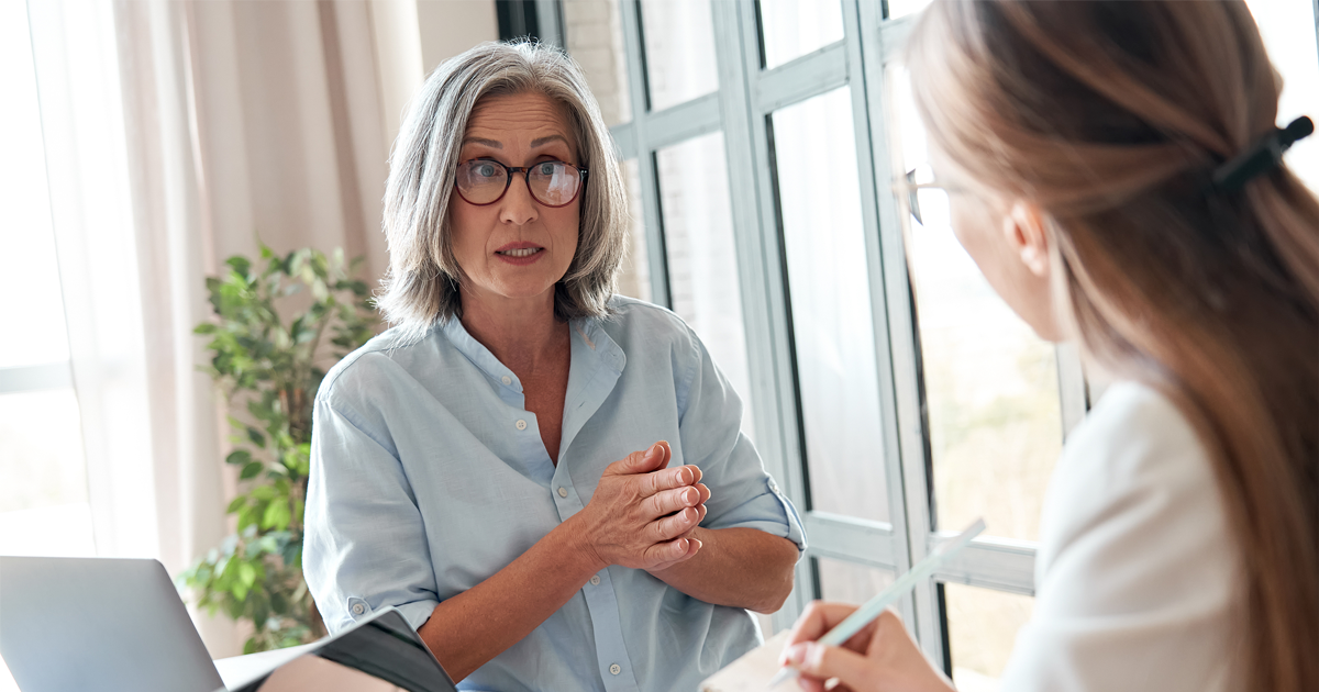 Mature female mentor or manager training young intern explaining sharing professional skills in office.
