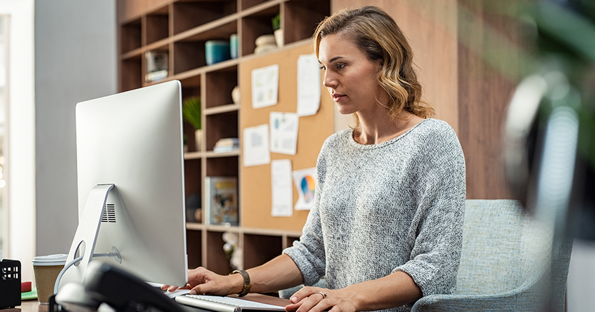 Mature businesswoman working on desktop computer at modern office.