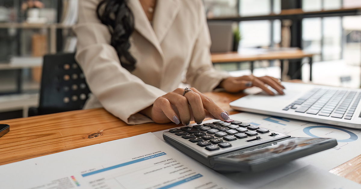 Close-up of businesswoman hands using a calculator to check company finances and earnings and budget