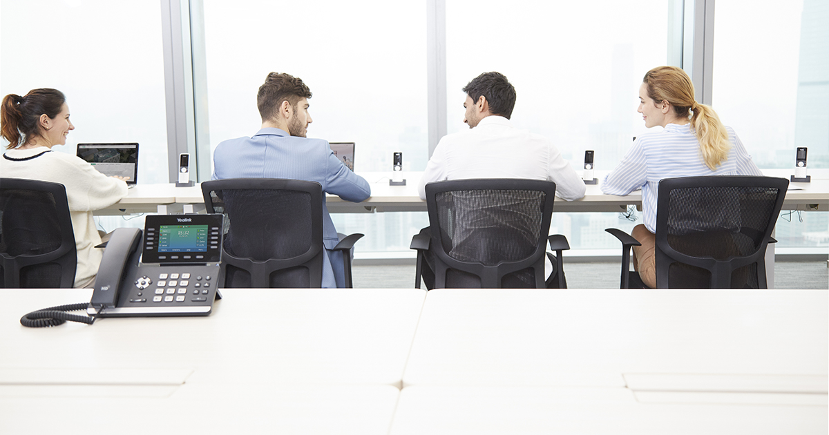 Business professionals sitting in conference room with desktop phone sitting on table. 
