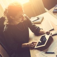 A woman sitting at her desk working on her tablet