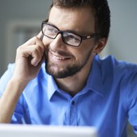 A young man sitting down on the phone