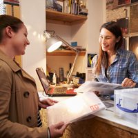 Two women talking sitting a desk.